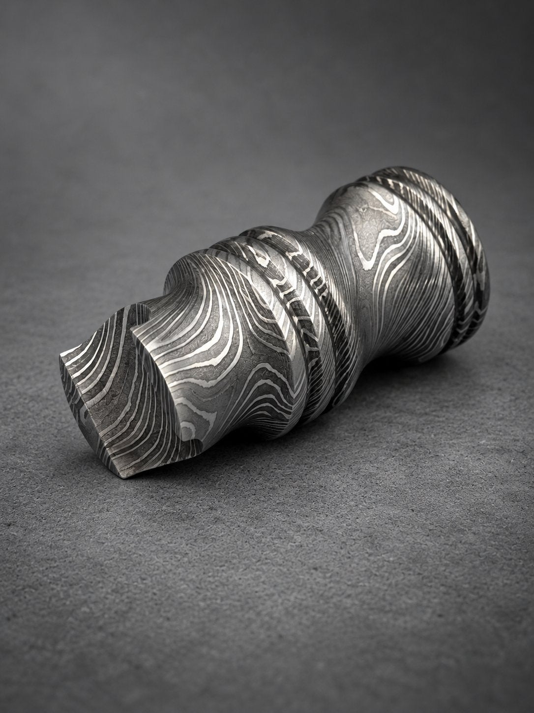 Close-up of Damascus steel cigar rest showing spiral etched layers on turned steel