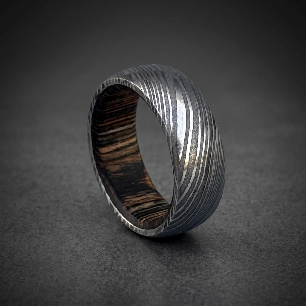 Domed Damascus steel wedding band photographed at an angle