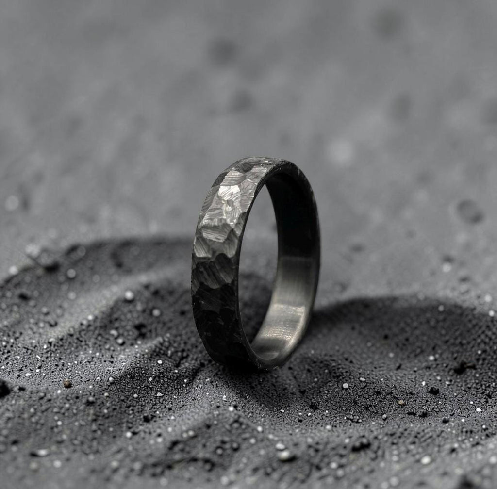 Minimalist black zirconium ring photographed at an angle against dark background