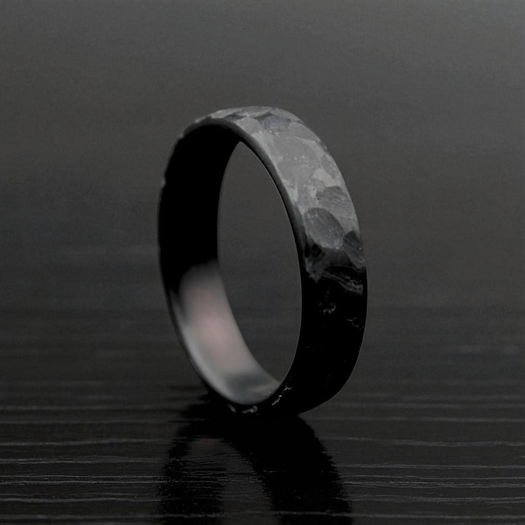 Black hammered zirconium ring standing on textured dark surface, front view