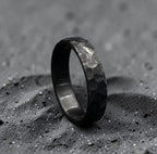 Close-up of zirconium wedding band hammered surface catching light across the black finish