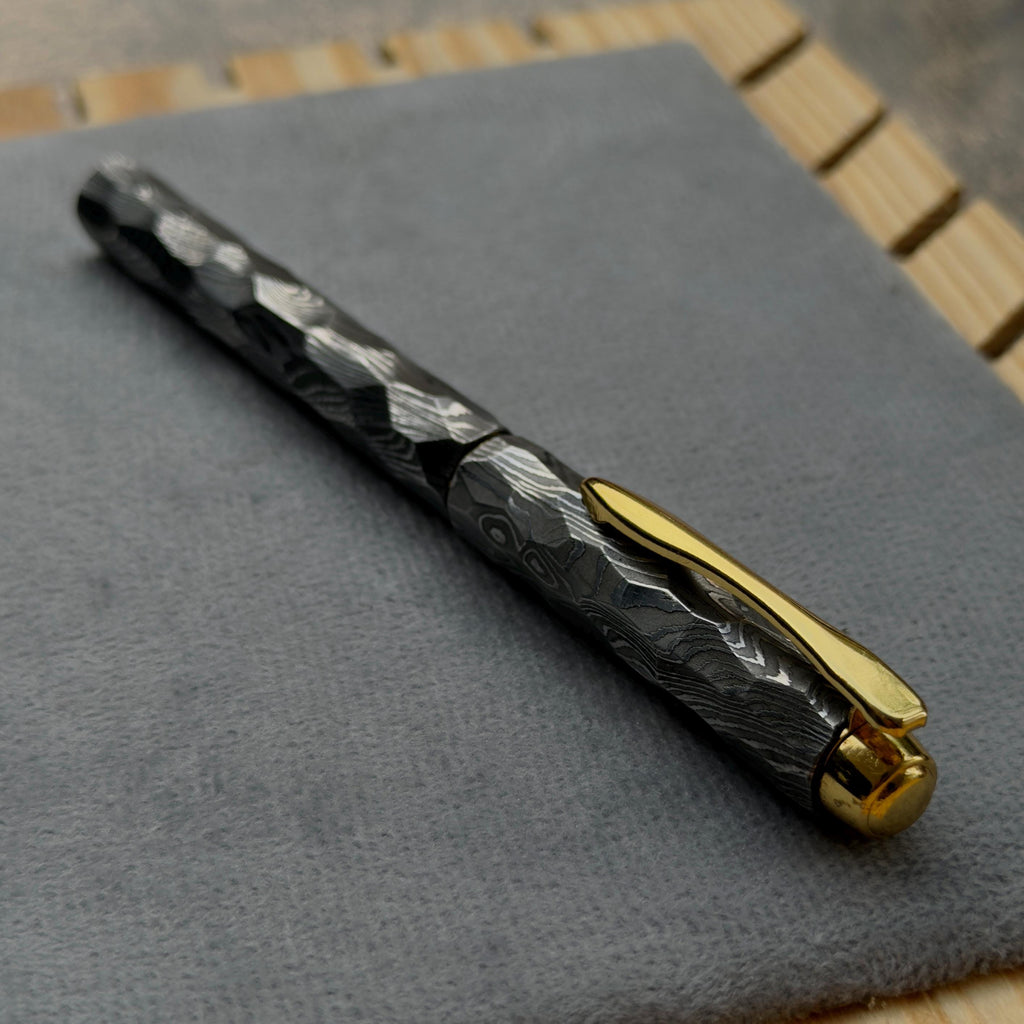 Close-up of faceted Damascus steel fountain pen barrel showing etched layers