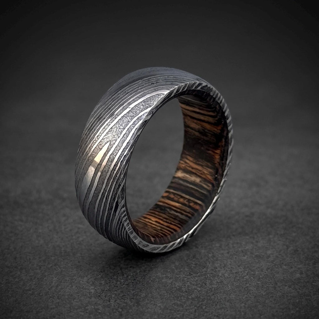 Close-up of dark wood inlay inside domed Damascus steel wedding band