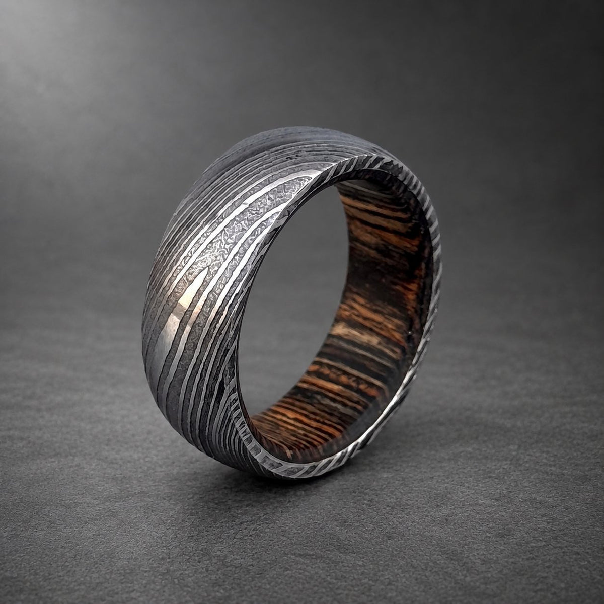 Close-up of dark wood inlay inside domed Damascus steel wedding band