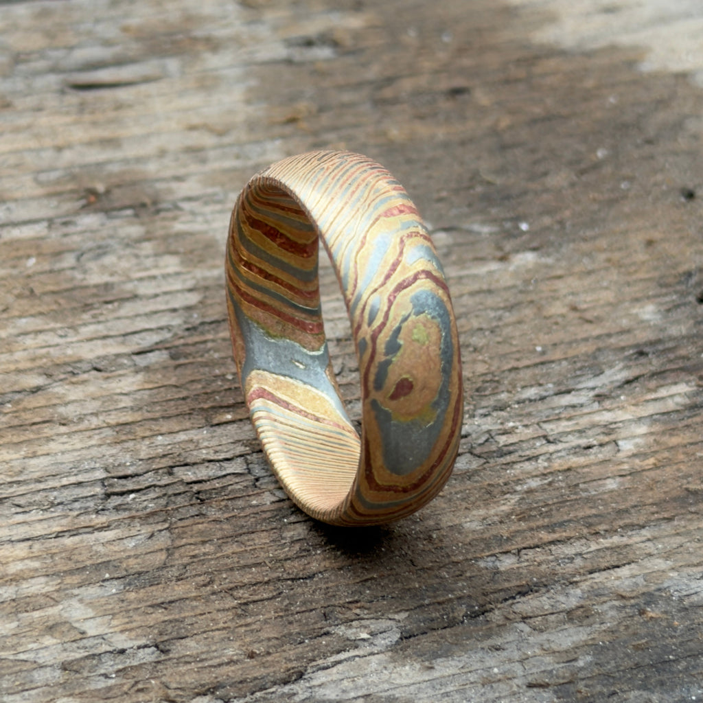 Mokume gane wedding band shown on dark textured surface