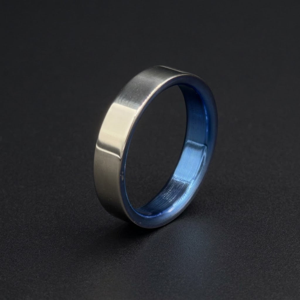 A brushed silver metal band ring with a vibrant blue anodized interior, shown standing upright on a dark gray background.