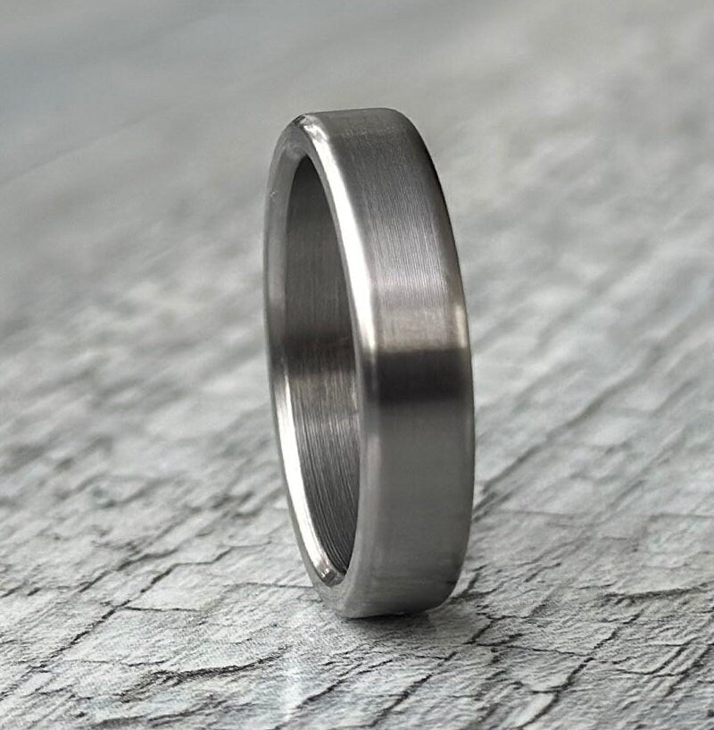 Brushed titanium wedding band worn on hand, minimalist engagement ring