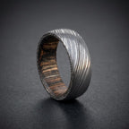 Close-up detail of etched Damascus steel layers on domed wood inlay ring