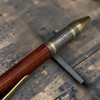 Damascus steel pen shown at an angle showing forged copper clip