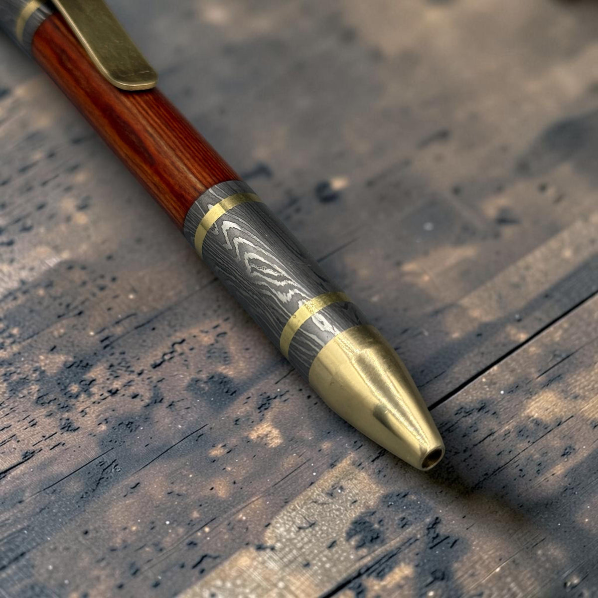 Damascus steel ballpoint pen close-up showing forged metal grain