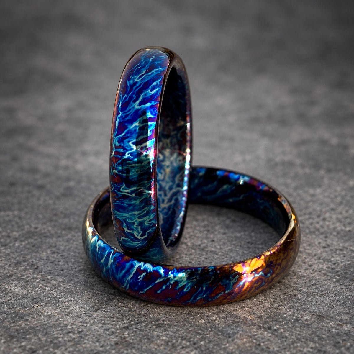 Two iridescent blue and purple rings with a swirling pattern. The rings are stacked on top of each other.