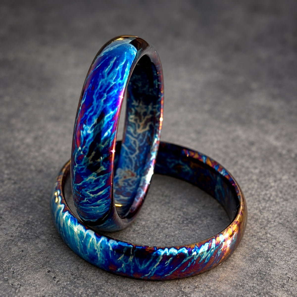 Two iridescent rings with a blue, purple and white pattern. The rings are stacked on top of each other.