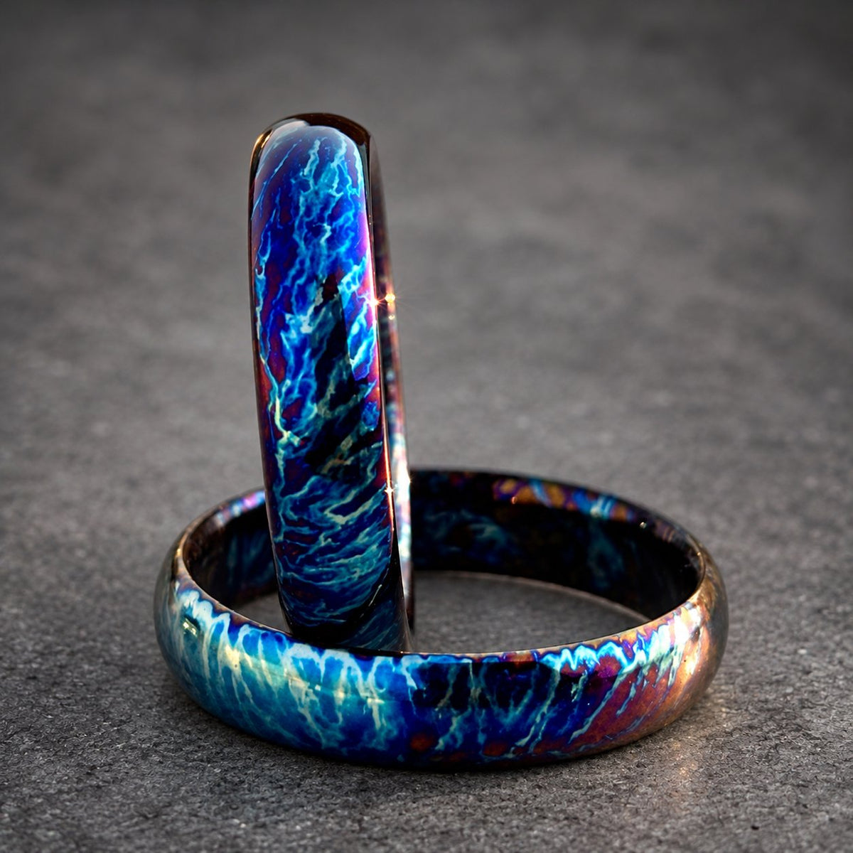 Two iridescent blue and purple rings with a swirling pattern. The rings are stacked on top of each other, view 5