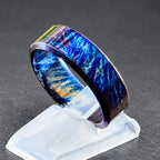 A blue and white titanium ring with a swirling pattern. The ring is on a white display stand.