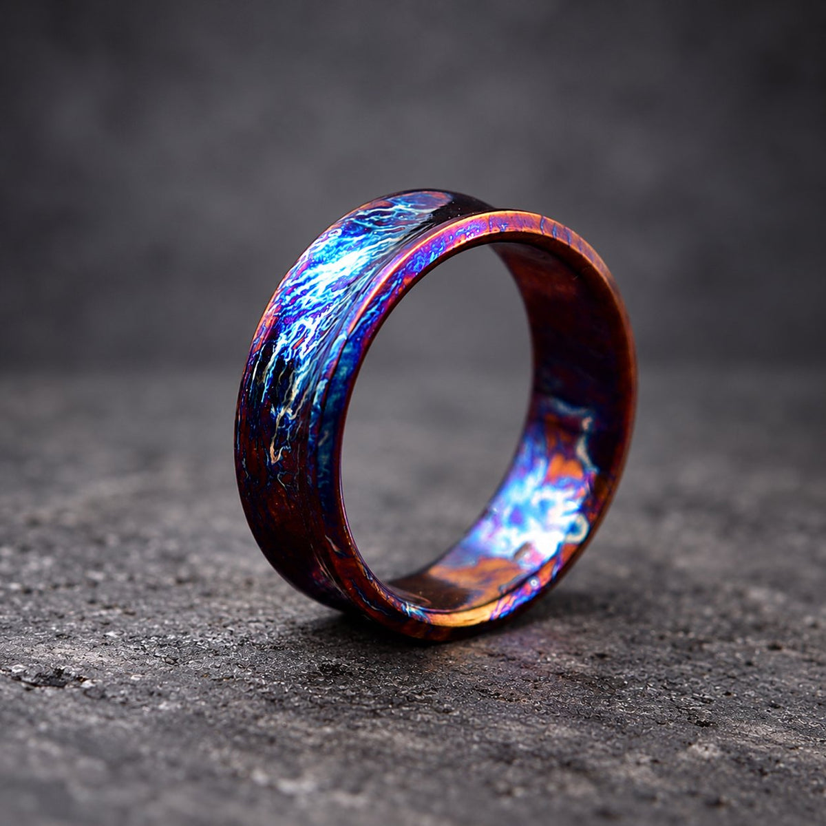 A wide, dark blue and purple ring with a textured, iridescent finish. The ring is made of metal and has a polished, shiny surface.