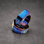 Two stacked rings with a blue and purple iridescent finish. The rings are made of metal and have a square shape.