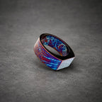 A wide, flat ring with a blue, purple and red marbled pattern. The ring is made of metal and has a square-shaped top.