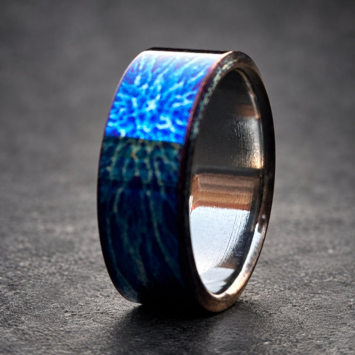 A blue and silver ring with a patterned design. The ring is made of metal and has a polished finish.