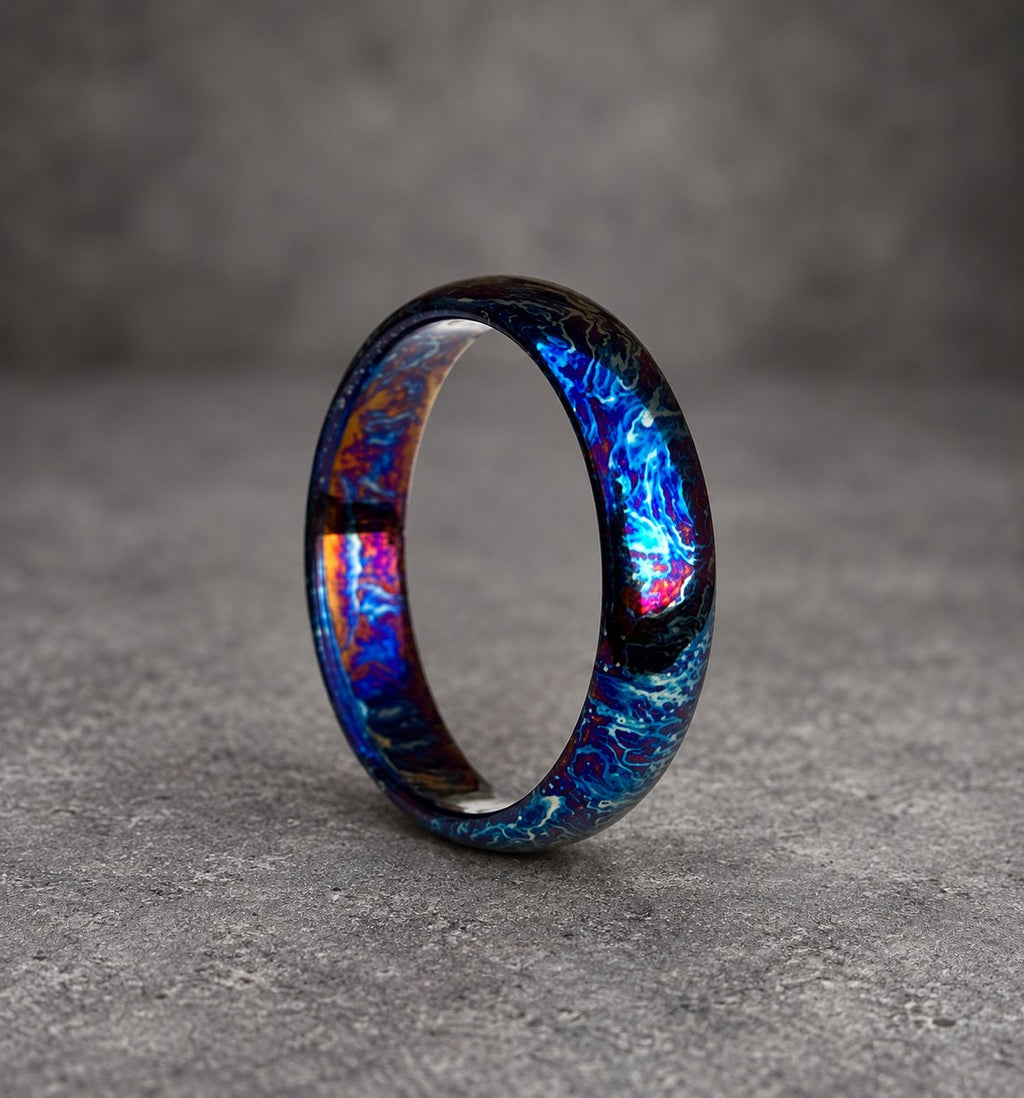 A blue, black and purple ring with a swirling pattern. The ring is made of metal and has a polished finish.