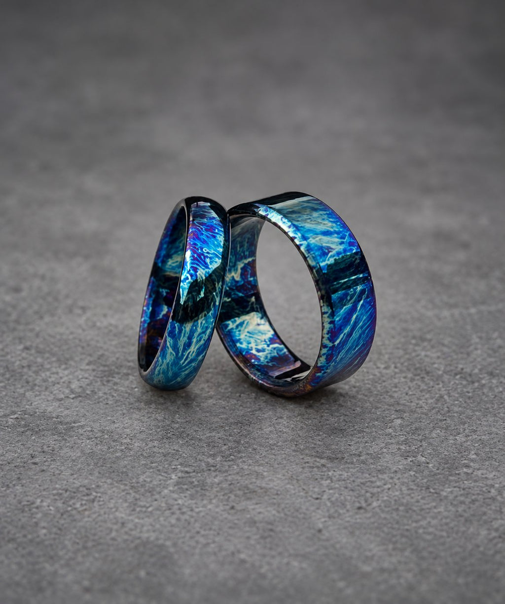 Two silver rings with a blue and purple iridescent finish. The rings are stacked on top of each other.