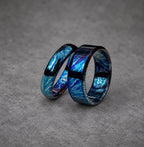 Two blue and black patterned rings, one slightly larger than the other, are stacked together. The rings have a metallic finish and a swirling pattern.