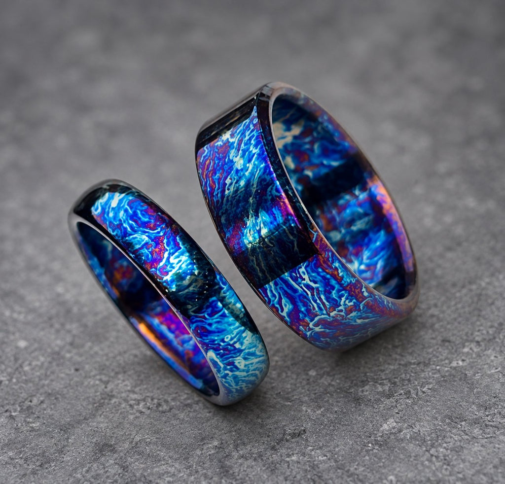 Two rings with a blue, purple and white swirling pattern. The rings are made of metal and have a polished finish.