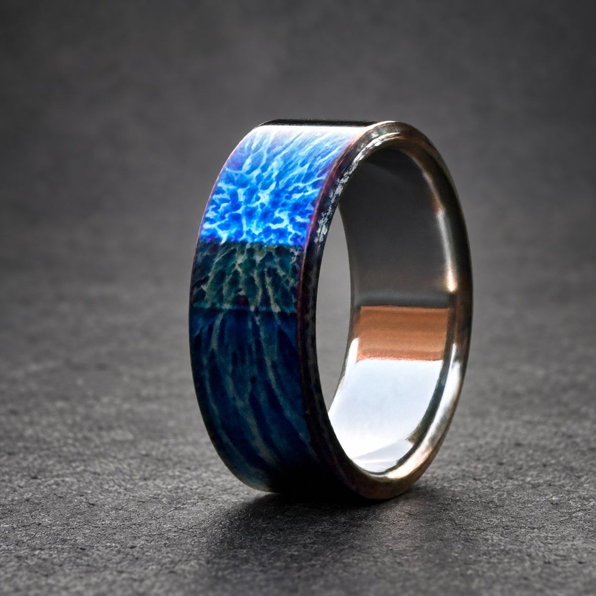 A blue and silver ring with a textured, swirling pattern. The ring is made of metal and has a polished finish.