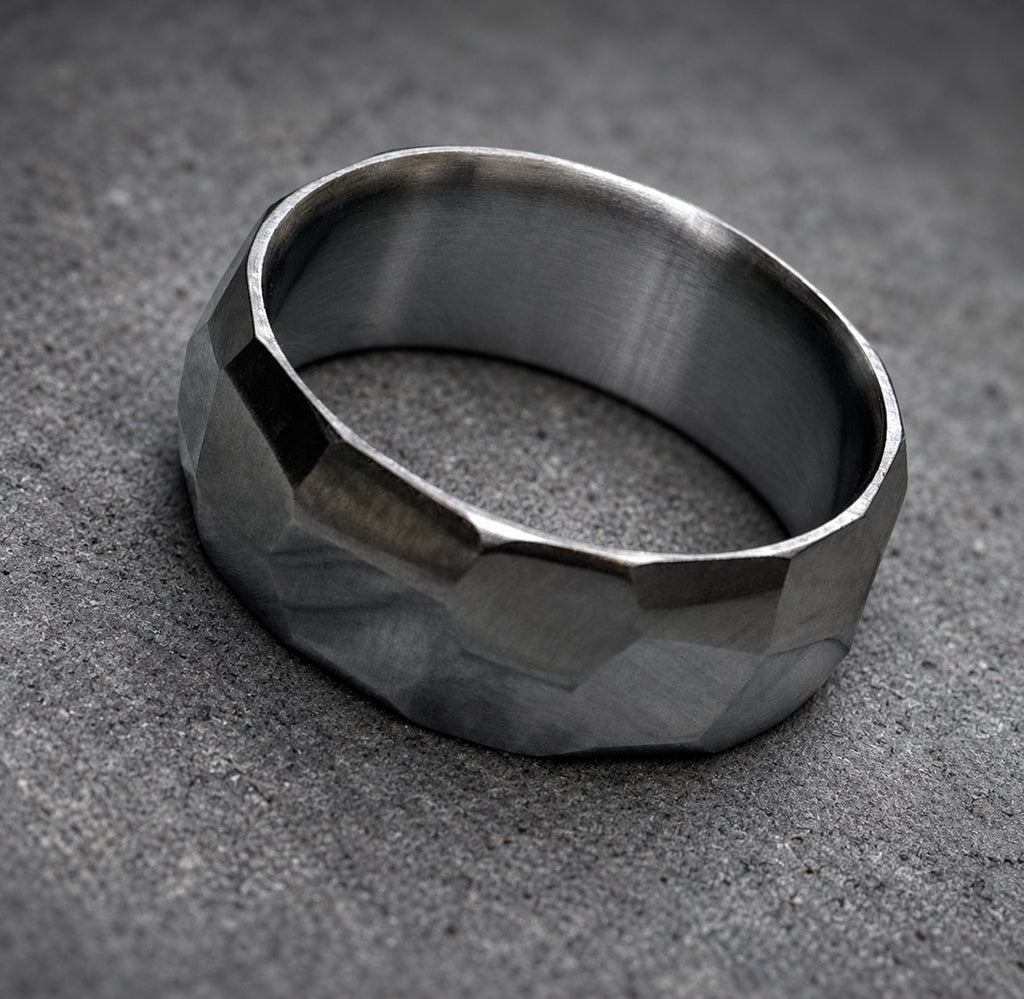 A dark gray hammered metal ring with a wide band.