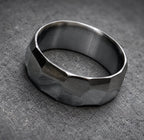 A dark gray hammered metal ring with a wide band.