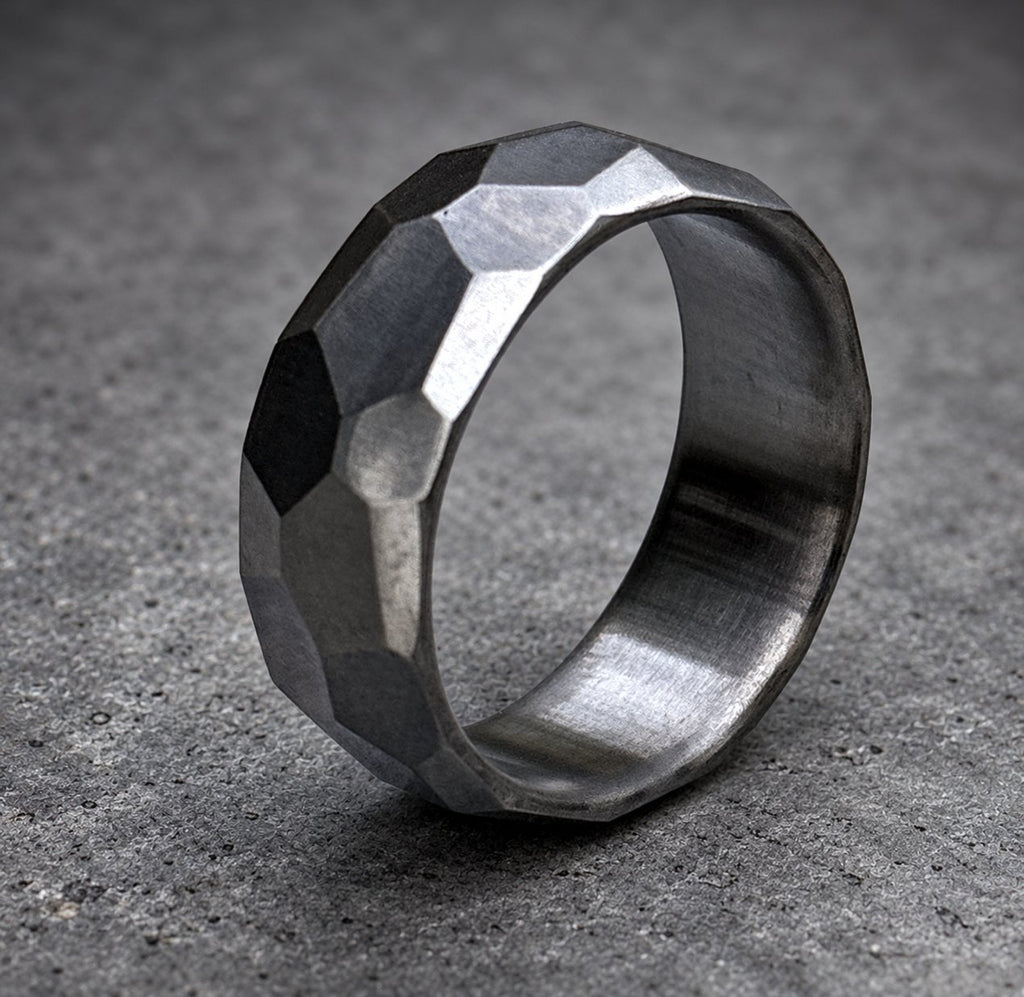 A silver ring with a textured, faceted design. The ring is made of metal and has a polished finish, view 4