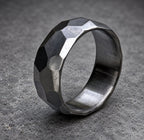 A silver ring with a textured, faceted design. The ring is made of metal and has a polished finish, view 4