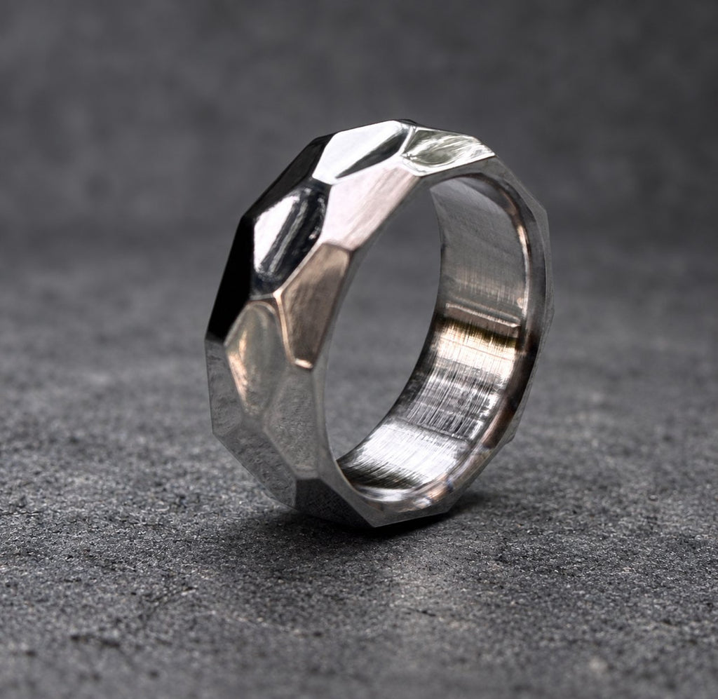 A silver ring with a faceted, geometric design. The ring is made of metal and has a brushed finish, view 8