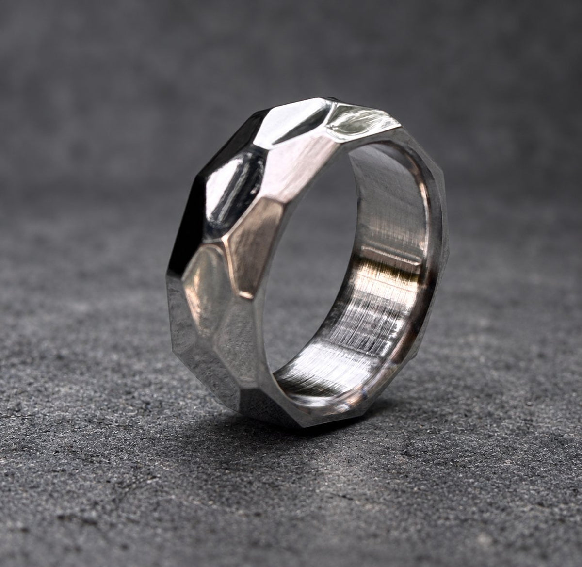 A silver ring with a faceted, geometric design. The ring is made of metal and has a brushed finish, view 8