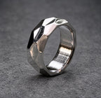 A silver ring with a faceted, geometric design. The ring is made of metal and has a brushed finish.