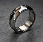 A silver ring with a geometric, faceted design. The ring is polished and has a brushed finish on the inside.