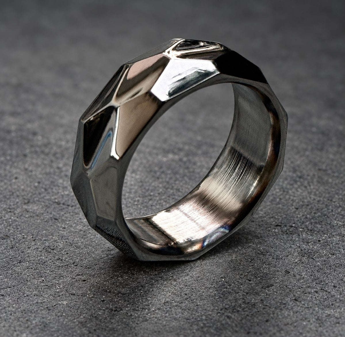 A silver ring with a geometric, faceted design. The ring is polished and has a brushed finish on the inside.