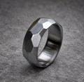 A silver ring with a faceted, geometric design. The ring is made of metal and has a brushed finish.