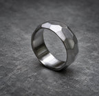 A silver ring with a textured, faceted design. The ring is made of metal and has a polished finish, view 3