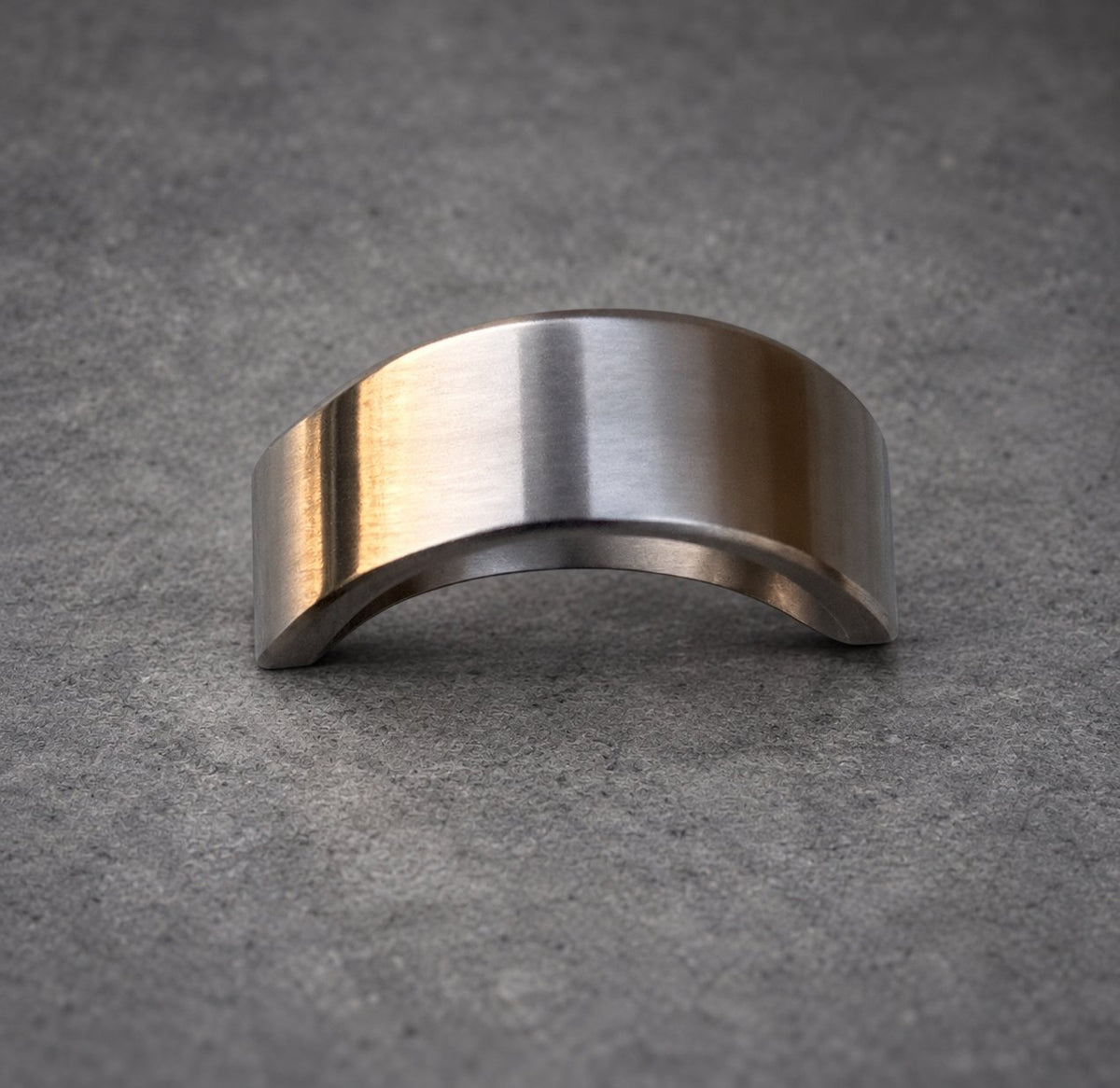 A silver metal ring with a curved, rounded shape. The ring is smooth and polished.