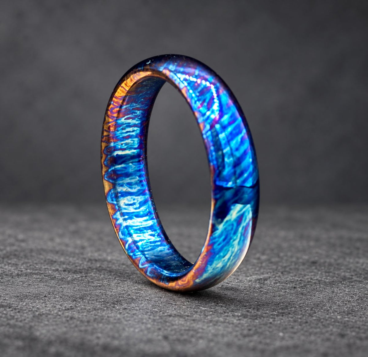 A blue and copper ring with a unique swirling pattern. The ring is made of metal and has a polished finish.