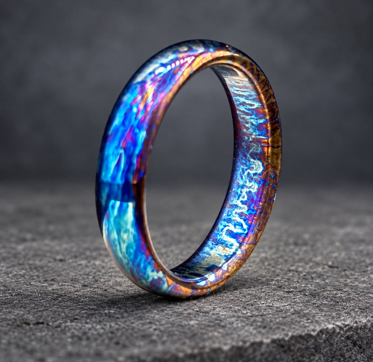 A blue, purple and copper colored metal ring with a smooth, polished finish.