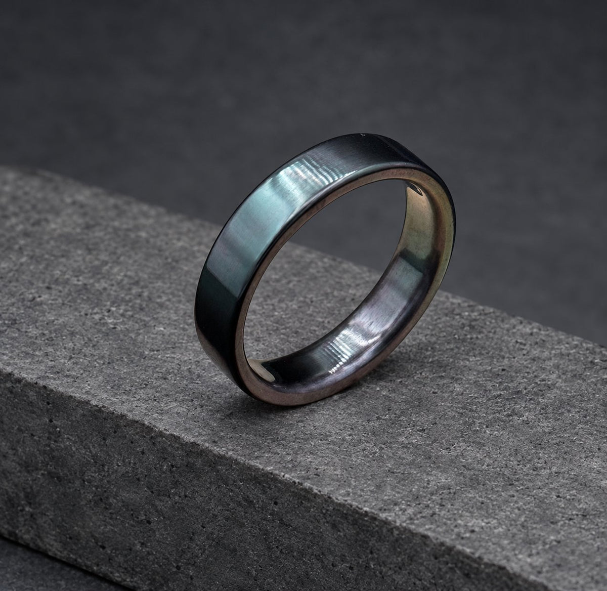 A black ring with a smooth, polished finish. The ring is made of metal and has a simple, classic design.