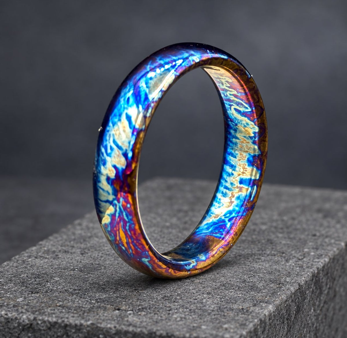 A blue, purple and gold ring with a unique, swirling pattern. The ring is made of metal and has a polished finish.