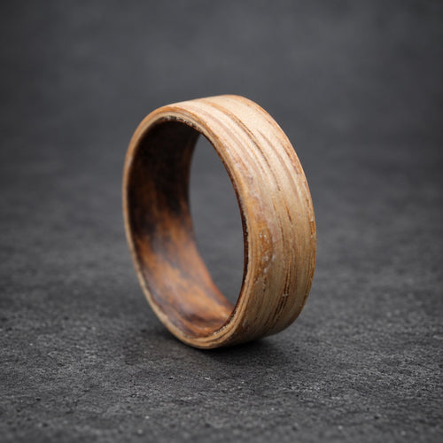 A wooden ring with a light brown outer layer and a darker brown inner layer. The ring is made of wood veneer and has a natural, rustic look.