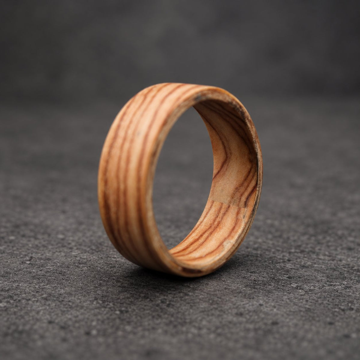 A wooden ring with a natural wood grain pattern. The ring is made of multiple layers of wood, creating a unique and interesting design.