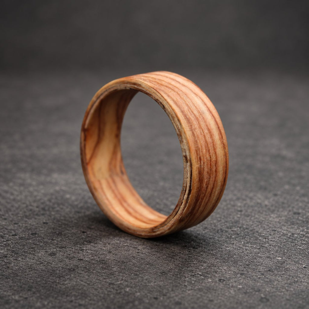 A wooden ring with a natural wood grain pattern. The ring is made of multiple layers of wood, creating a unique and intricate design.