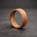 A wooden ring with a natural wood grain pattern. The ring is made of multiple layers of wood, creating a unique and intricate design.