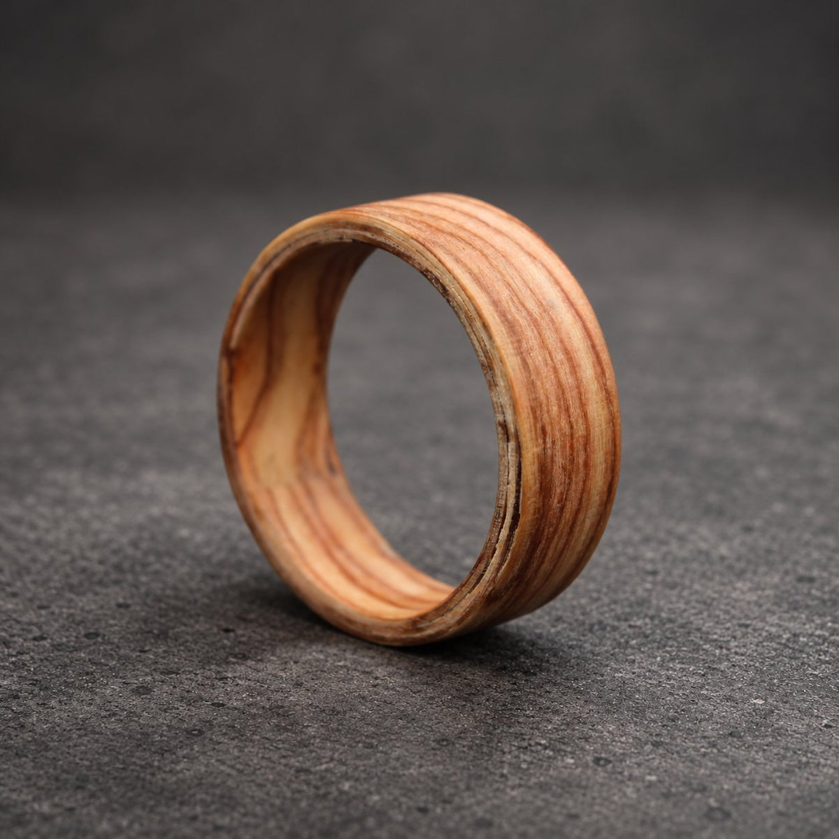 A wooden ring with a natural wood grain pattern. The ring is made of multiple layers of wood, creating a unique and intricate design.
