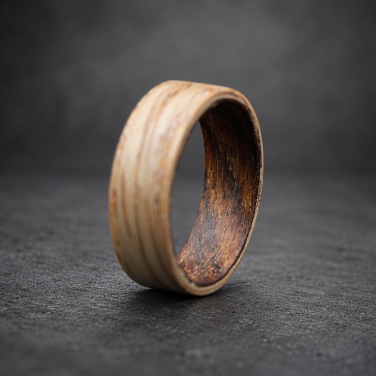 A wooden ring with a light brown outer layer and a dark brown inner layer.