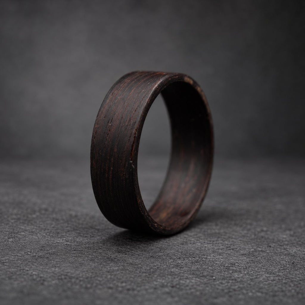 A dark brown wooden ring with a smooth, polished finish. The ring is thick and has a wide band.